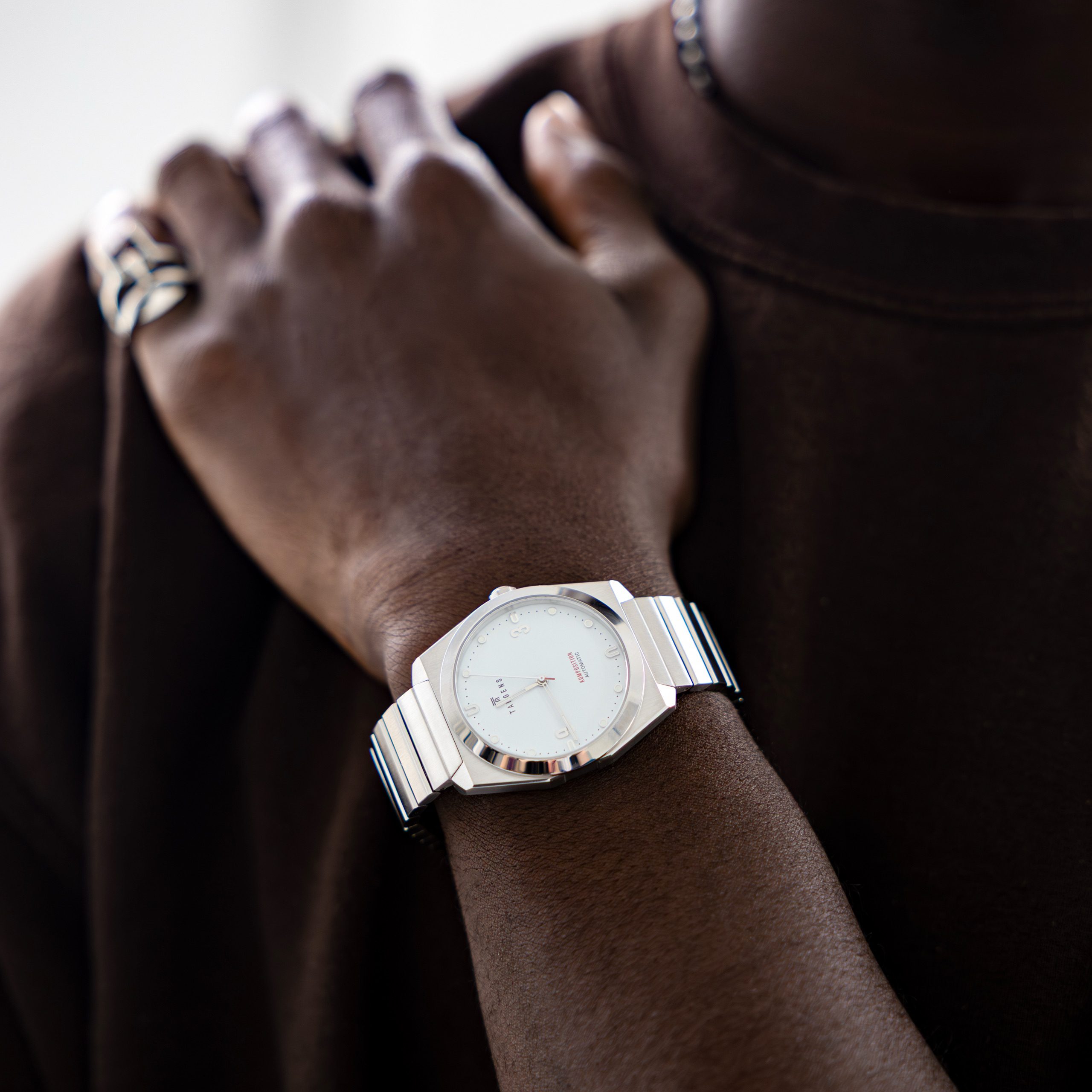 A hand on a shoulder with a Komposition Automatic Bright White on the wrist