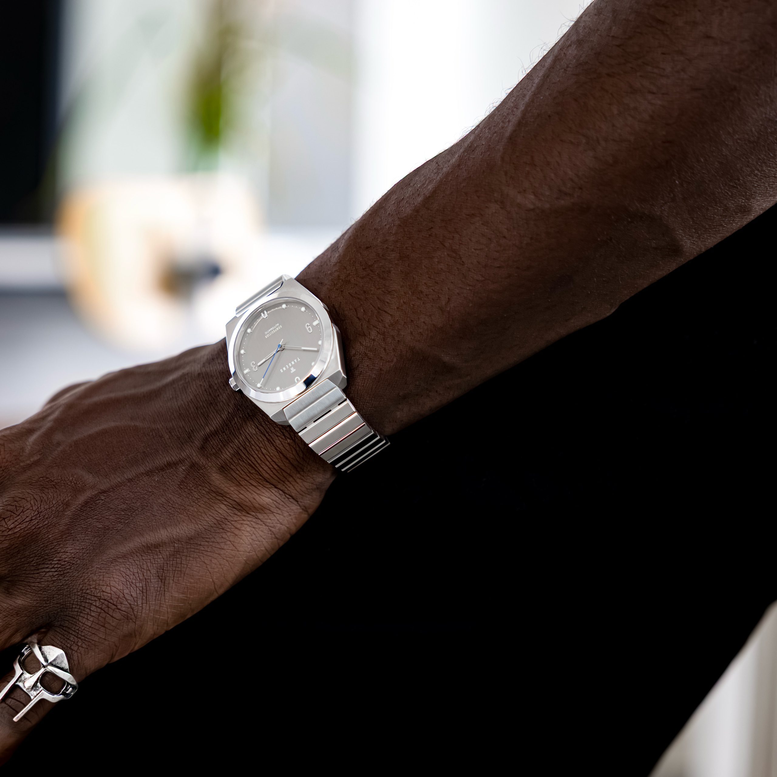 Close-up of a Komposition Automatic Matte Steel on a wrist, a silver ring on the hand
