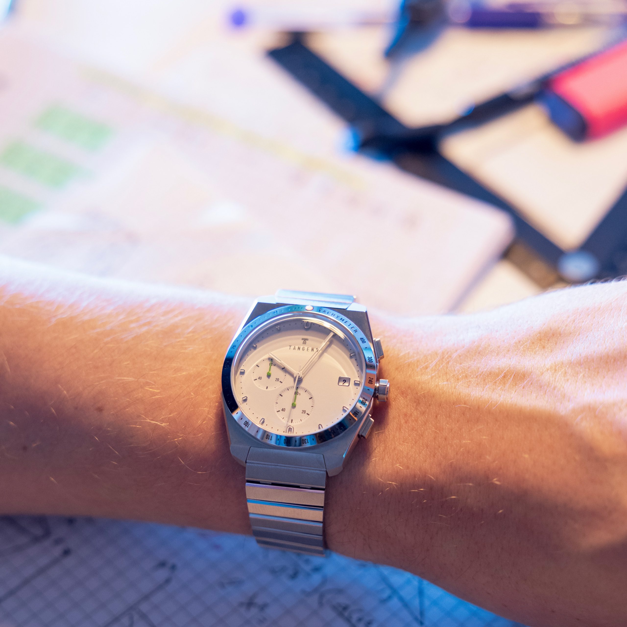 A Komposition Chronograph Soft Stone on a wrist over a notebook of sketches